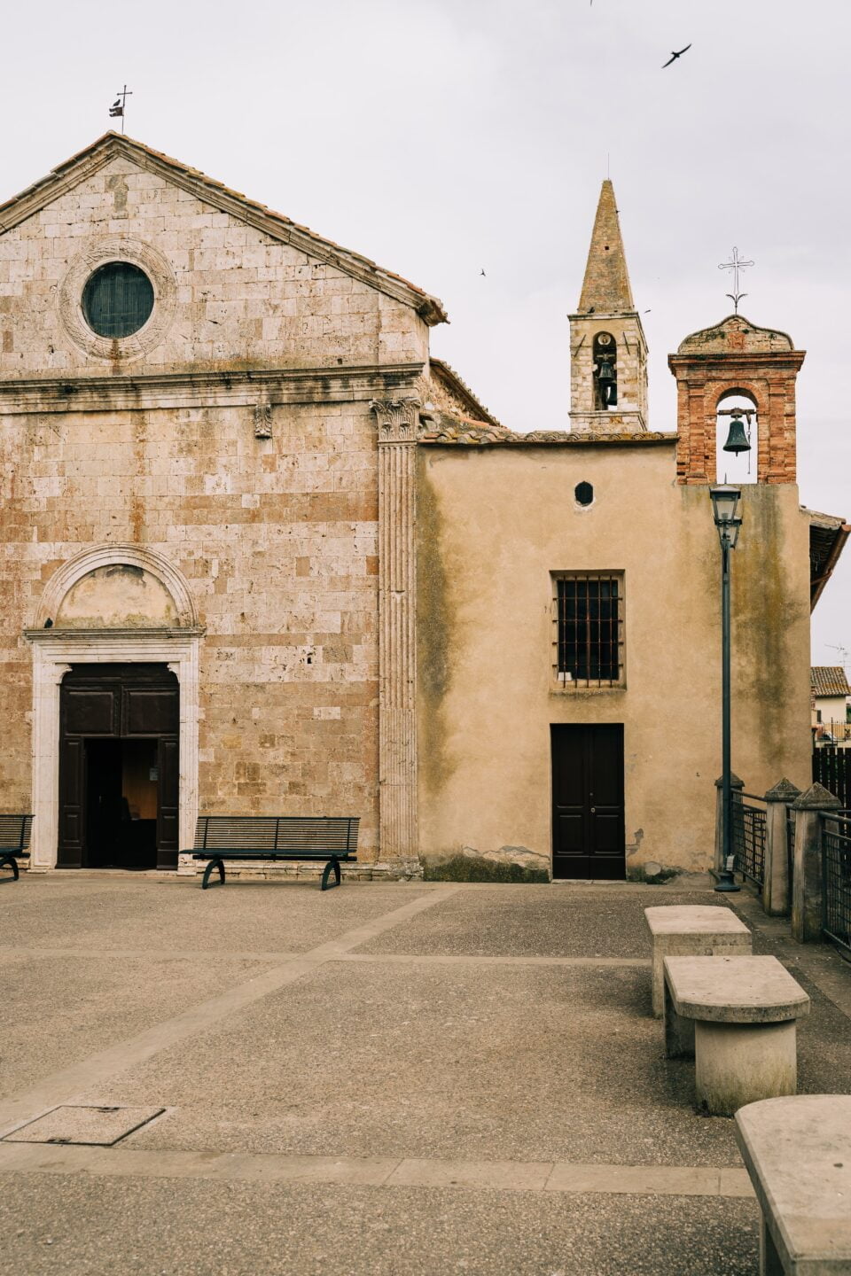 Historic stone church with bell tower and benches.